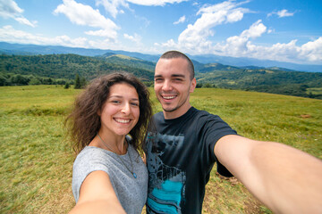 Young couple hugs and take selfie with amazing mountain landscape background