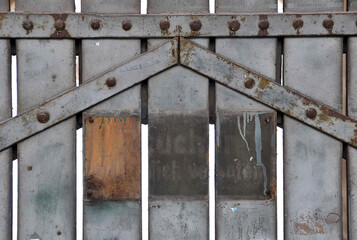 altes Holztor mit rostigen Metallbeschlägen, graues Industrietor mit Graffitiy