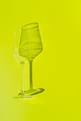 Champagne glass lies on lemon green surface. Glass with hard shadow 