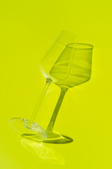 Champagne glass lies on lemon green surface. Glass with hard shadow 