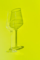 Champagne glass lies on lemon green surface. Glass with hard shadow 