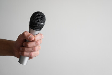 Hand holding a silver microphone on the left side of the image.
