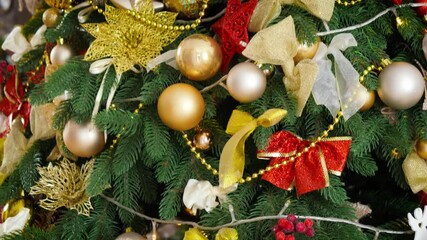 Panning closeup shot of beautiful decorated Christmas tree with lots of baubles, light garlands and ribbons. Winter holidays background or backdrop. - Powered by Adobe