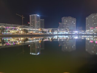 Fototapeta na wymiar Reflection Of Illuminated Buildings In River At Night