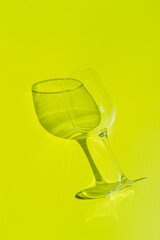 Wine glass lies on lemon green background. 