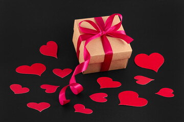 Gift and Red paper hearts on a black background. The Concept Of Valentine's Day. Festive texture for the holidays. Composition of a flat layer. Heart, decor.