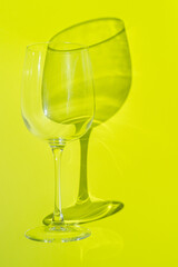 Wine glass lies on lemon green background. 