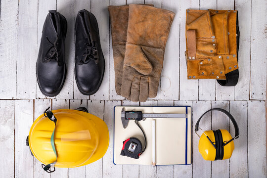 Workwear for a production worker on a white table. Personal protection accessories and measuring tools used at work.