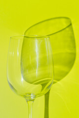 A part of wine glass lies on lemon green background. 