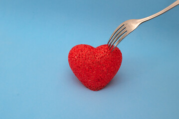 fork pricks a red heart on a blue background