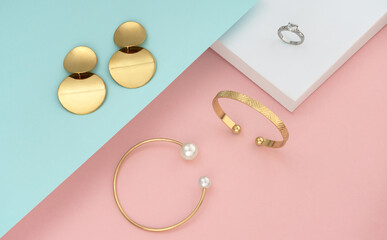 Top view of golden women accessories on pastel colors background