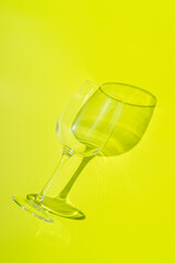 Wine glass lies on lemon green background. 