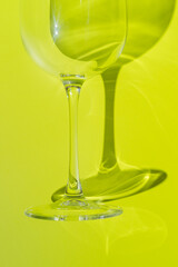 A part of wine glass lies on lemon green background. 