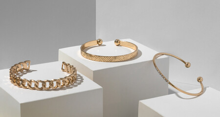 Three golden bracelets on white geometric paper cubes - obrazy, fototapety, plakaty
