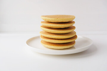 Freshly cooked soft delicious gluten free pancakes stacked on white plate, close up. Space for text. Healthy sweet food.