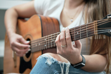 girl's hands playing an acoustic guitar