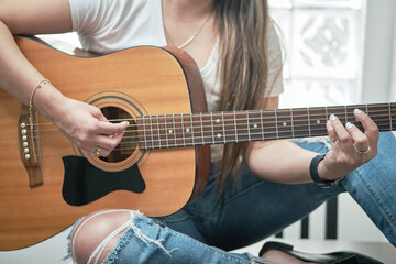 girl's hands playing an acoustic guitar