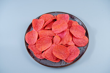 Red potato chips with salt on a gray background