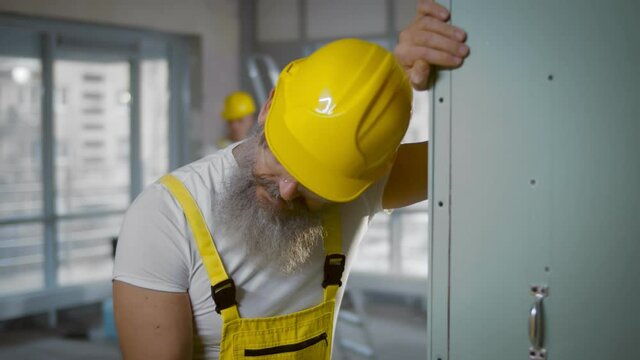 Senior construction worker sick and coughing in renovating apartment