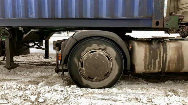 the truck got stuck in the snow. Wheels of Truck with Cargo Trailer Slide on Dirty Snow on the Road.