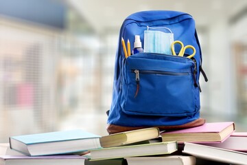 Classic school backpack with colorful school supplies and books on desk.