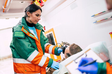 Paramedics are working with a senior man patient while he lies on a stretcher in an ambulance.
