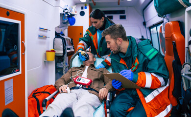 Doctors emergency or paramedics are working with a senior man patient while he lies on a stretcher in an ambulance.