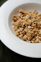 granola in a white plate on a table with a green tablecloth