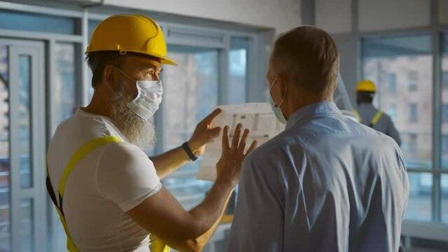 Back view of engineer and architect working on construction site and inspect blueprint of project