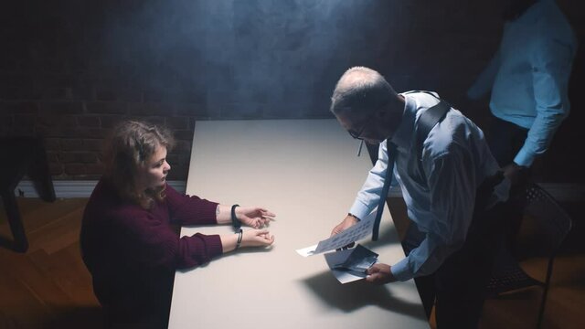 Two police officers and woman criminal in interrogation room
