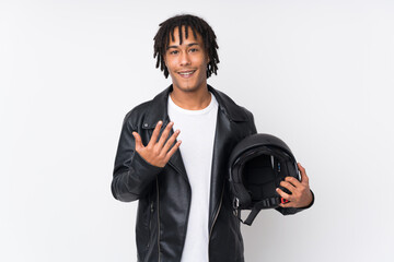 Young african american man holding a motorcycle helmet isolated on white background inviting to...