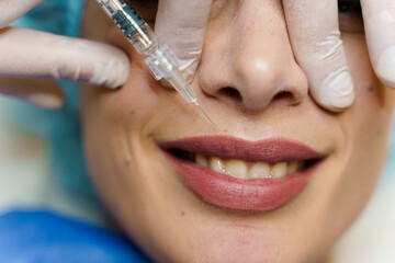 Lips augmentation injections for attractive girl. Plastic surgeon does injection in lip in medical...