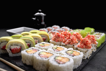 Sushi set of different rolls, with flying fish caviar, tobiko, shrimp, eel, salmon, avocado, sticks and soy sauce