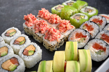 Sushi set of different rolls, with flying fish caviar, tobiko, shrimp, eel, salmon, avocado, sticks and soy sauce