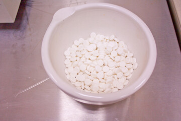 Production of tablets on a rotary press in a pharmaceutical laboratory. Trial batch. Ready-made tablets in a mortar.