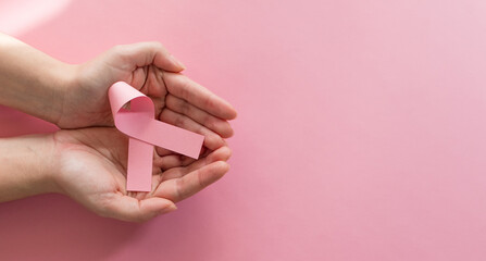 Woman hands holding pink ribbon, breast cancer awareness. World cancer day concept.