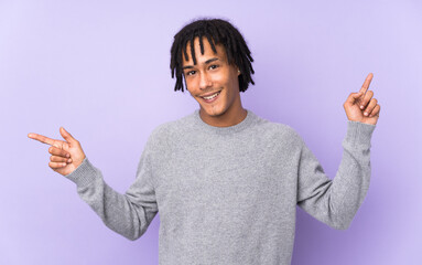 Young african american man isolated on purple background pointing finger to the laterals and happy