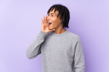 Young african american man isolated on purple background shouting with mouth wide open to the...
