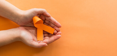 Woman hands with orange ribbons, Leukemia Cancer Awareness and Multiple Sclerosis Awareness. World cancer day concept.