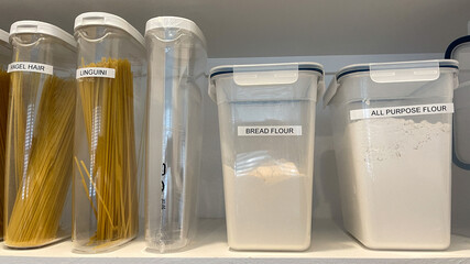 An organized pantry shelf with various types of pasta and flour