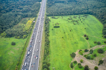 High angle aerial view of traffic on highway. Forest and fields around
