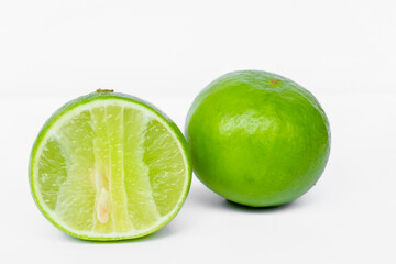 A green lemon cut in half on a white background close up.