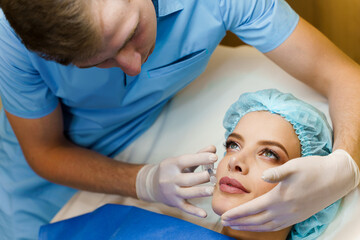 Lips augmentation injections for attractive girl. Plastic surgeon does injection in lip in medical...