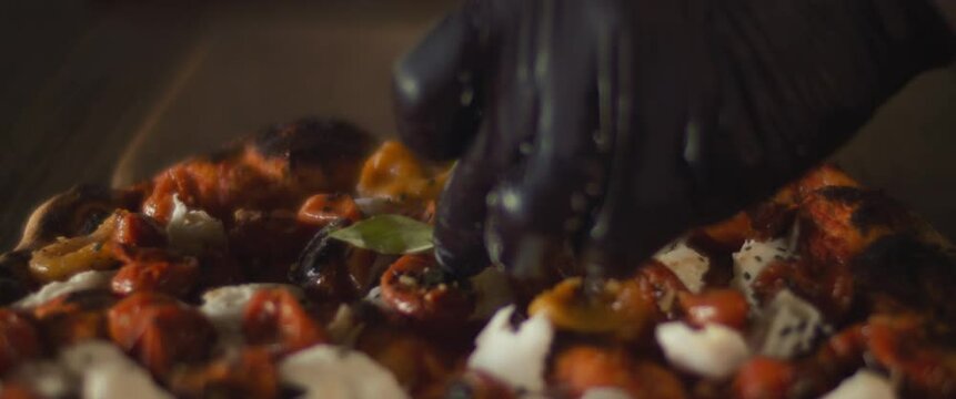 Chef spreading basil leaves over a ready burrata al taglio pizza. Close up, slow motion
