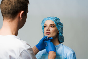 Lips augmentation injections for attractive girl on white background. Plastic surgeon does...