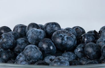 Close up of fresh ripe blueberries in bowl isolated on white with copy space for text. Bilberries on a white background. Concepts of healthy, vegan, vegetarian eating, dieting .
