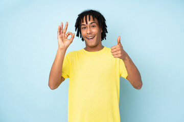 Obraz na płótnie Canvas Young african american man isolated on blue background showing ok sign and thumb up gesture