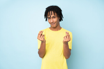 Young african american man isolated on blue background making money gesture