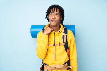 Young mountaineer african american man with a big backpack isolated on a blue background thinking...