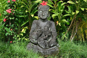 Indonesia Bali - Ubud Handmade stone buddha statue with red Hibiscus flower